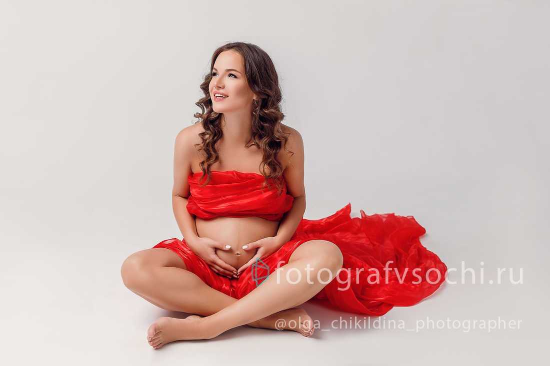 Беременная девушка сидя на полу