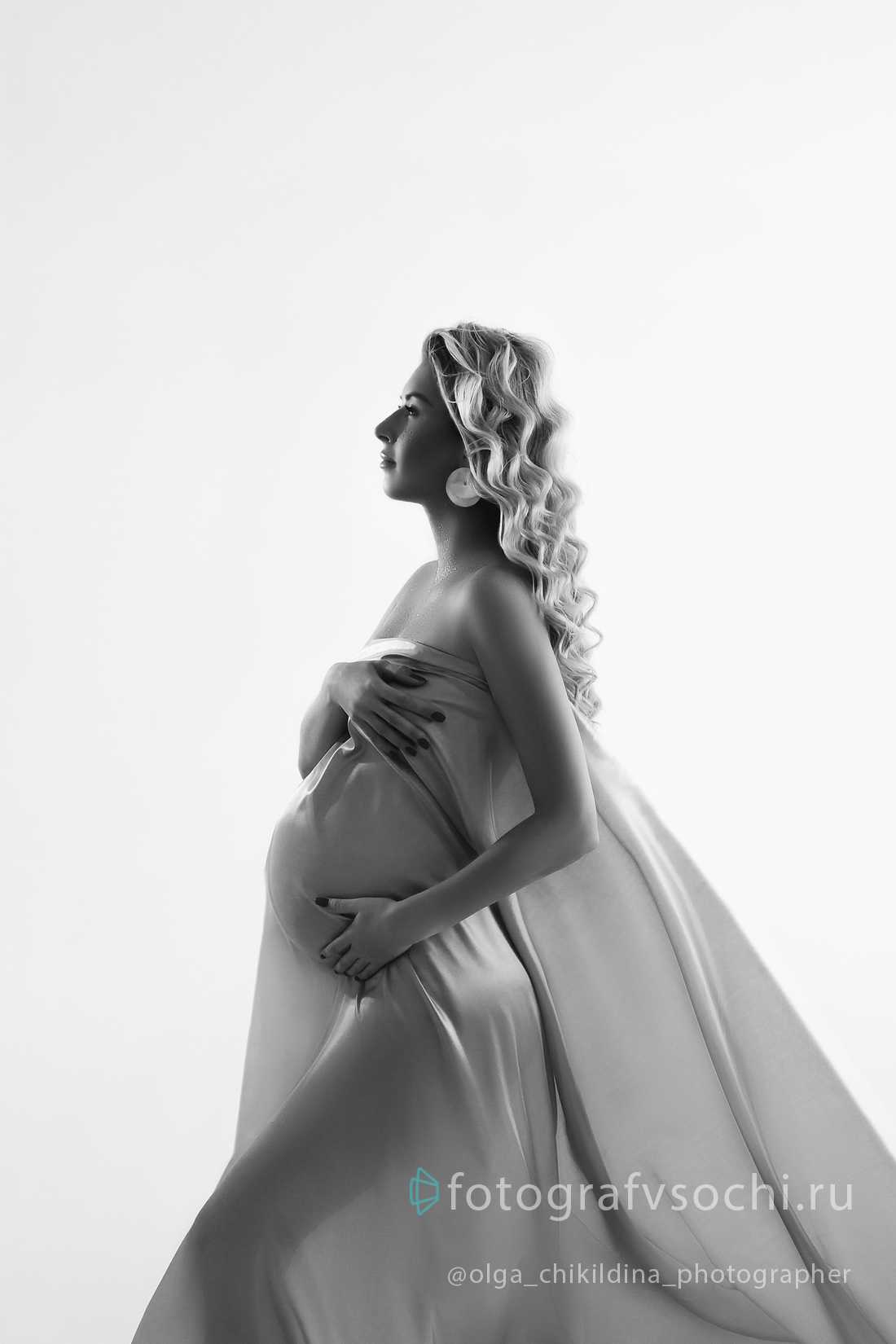 Профиль беременной девушки одетой в прозрачную ткань