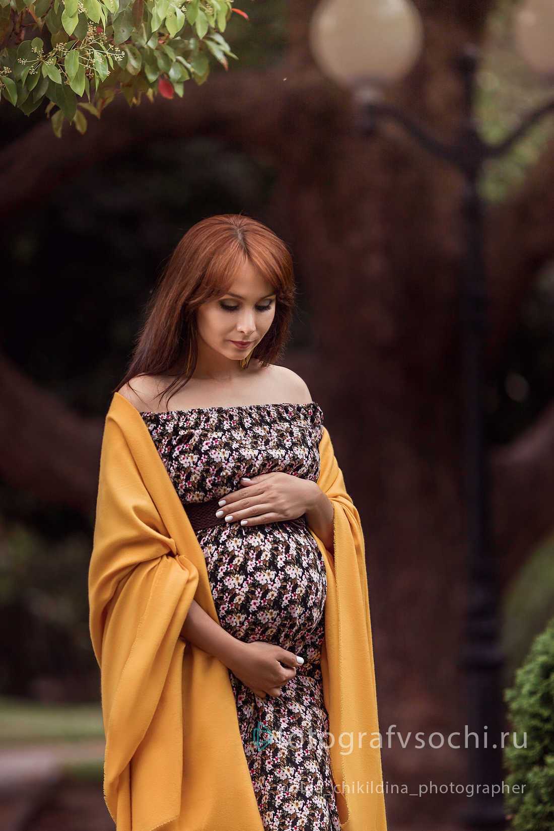 Беременная женщина гладит живот и смотрит на него