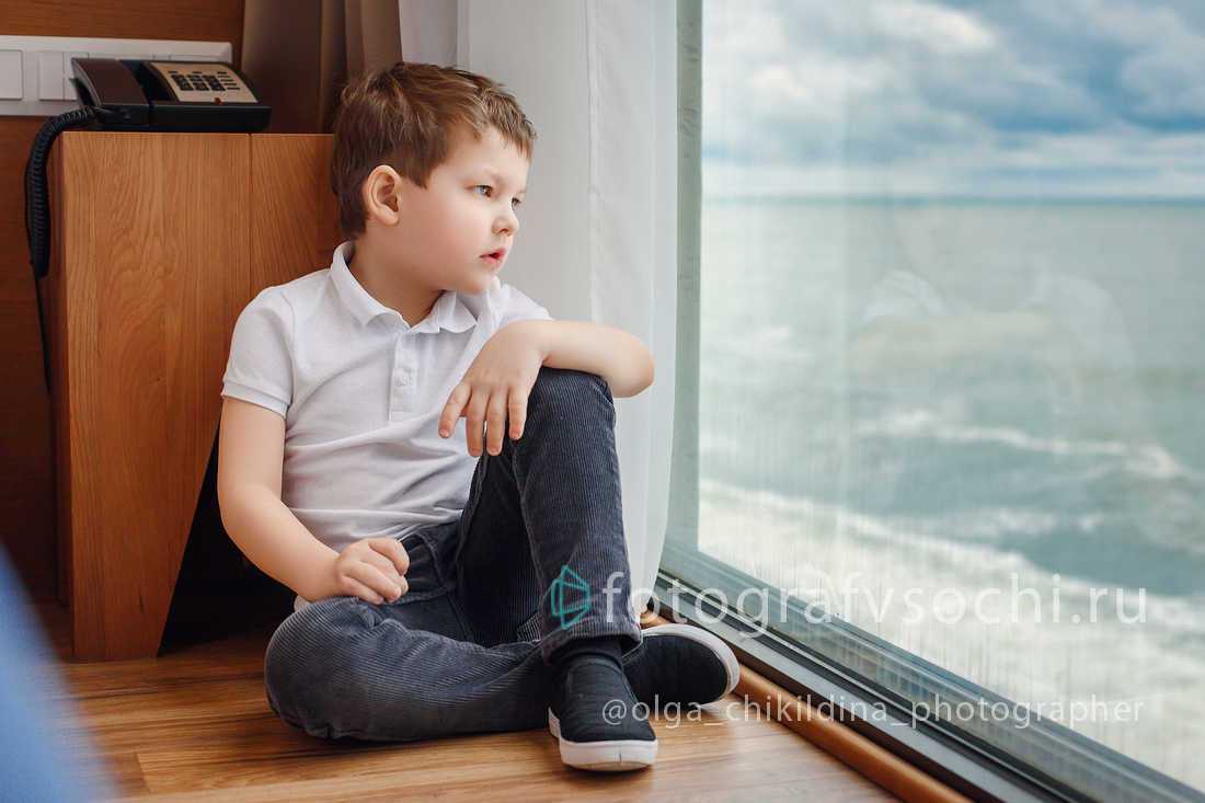 Мальчик смотрит на море из окна