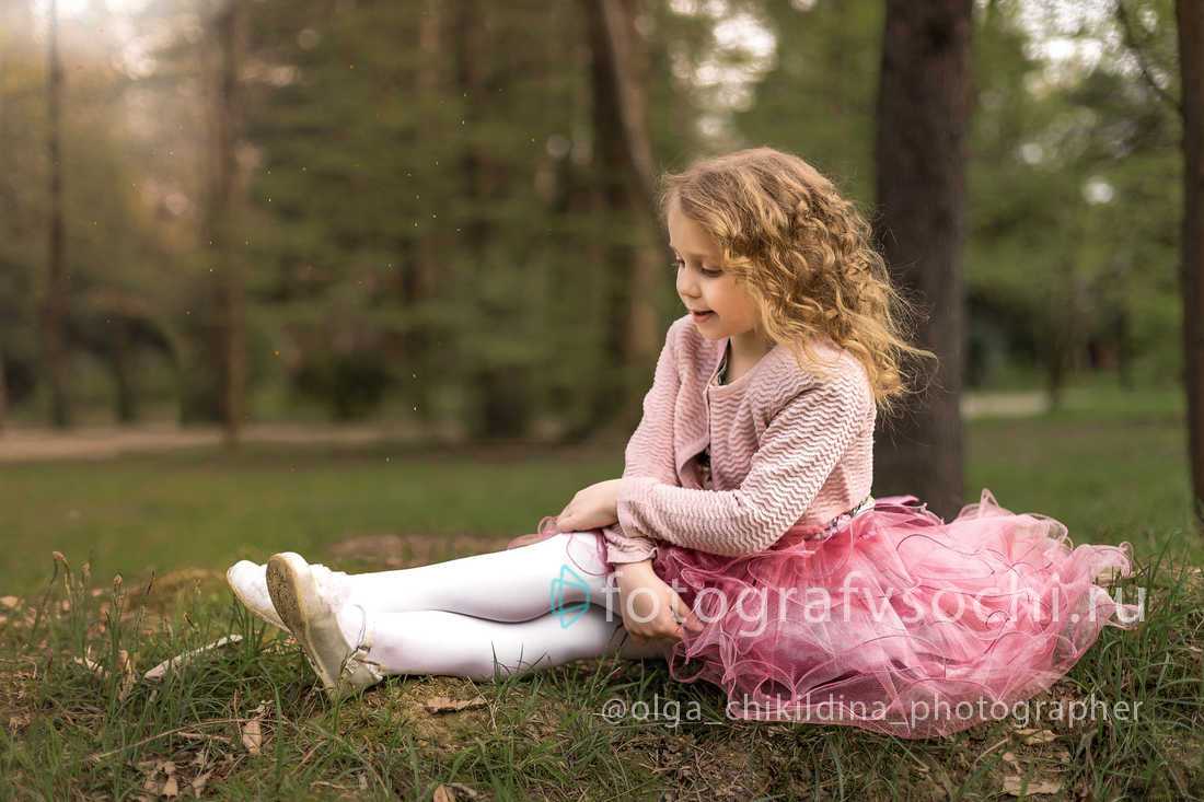 Девочка в розовом сидит на траве