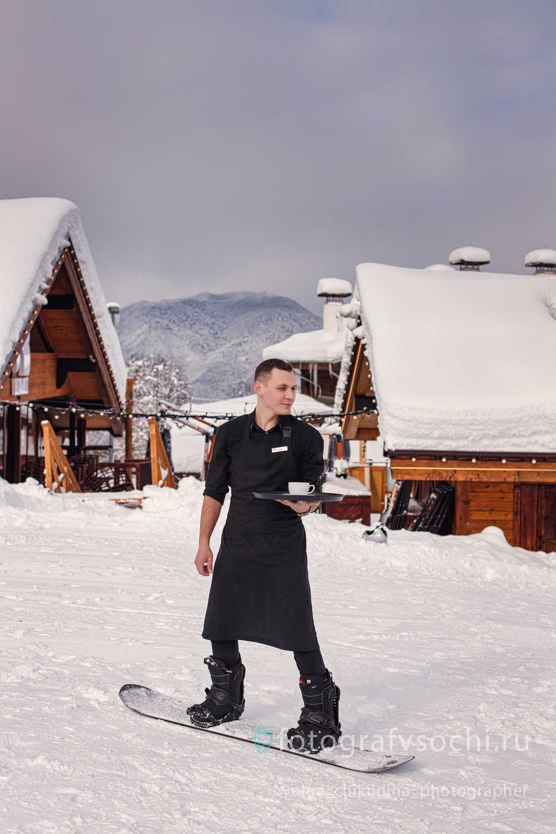 Официант на сноуборде с подносом и чашечкой кофе