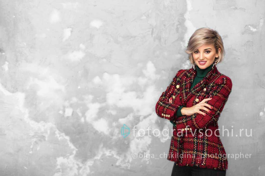 Девушка в клетчатом пиджаке на фоне стены