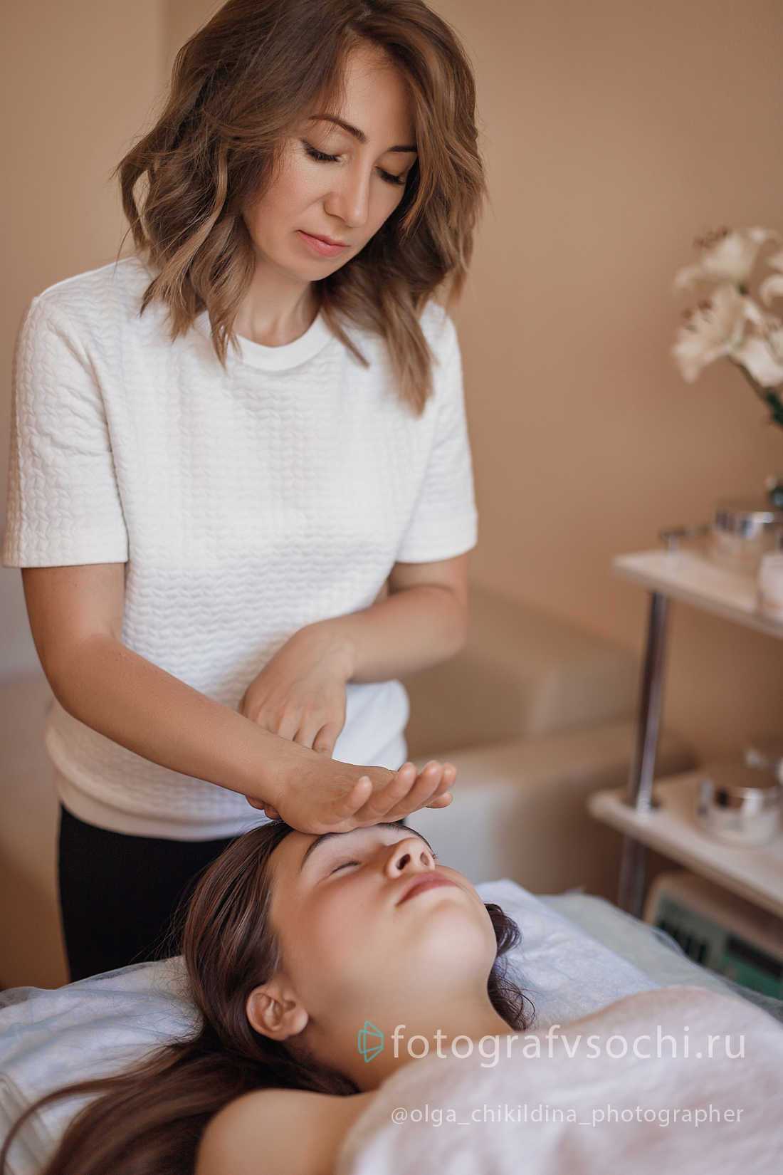 Женщина делает массаж лица пациентке